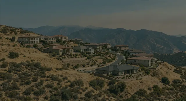An Eastern Washington hillside neighborhood near dry hills with smoke in the distance